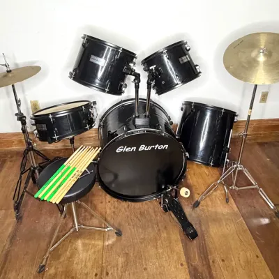 Glen Burton five-piece black drum set including cymbals, bass pedal, drum throne, and several pairs of drumsticks.