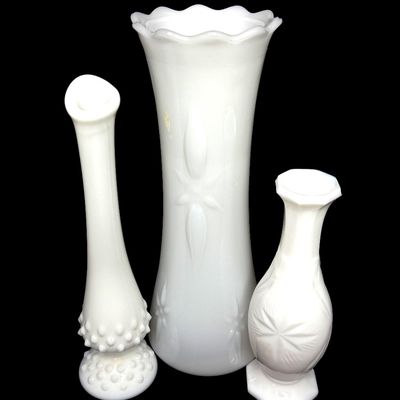 Trio of vintage white milk glass vases in varied patterns, including Fenton hobnail and floral cut designs.
