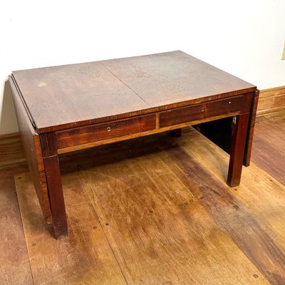 Vintage dark wood drop-leaf coffee table with two shallow drawers, showing minor surface wear.