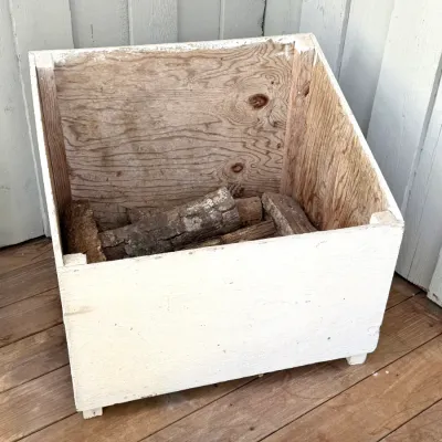 Handmade painted wooden firewood storage box with a slanted top, containing several logs.