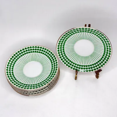 Set of vintage Neiman-Marcus porcelain saucers featuring a green shamrock pattern, radial green lines, and gold rims.