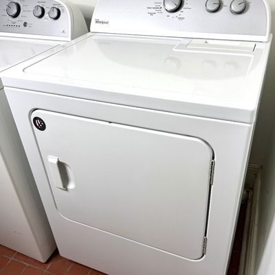 White Whirlpool electric clothes dryer featuring a top-mounted lint trap, mechanical dial controls, and a front-loading door.