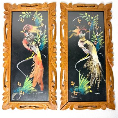 Pair of vintage Mexican feather art paintings featuring colorful birds set on a black background, framed in hand-carved wooden frames.