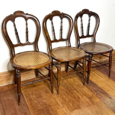 Trio of antique Victorian balloon-back side chairs with woven cane seats and turned legs.