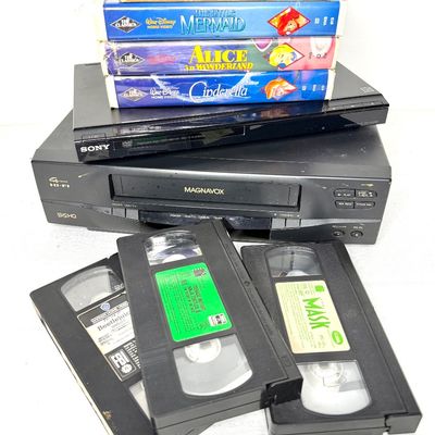 Magnavox 4-head Hi-Fi VCR player and a slim Sony DVD player, stacked beneath a selection of vintage VHS tapes in clamshell and slipcase...