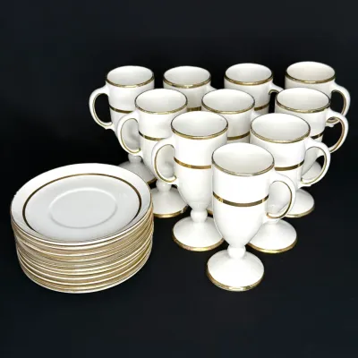 Set of ten white porcelain Irish coffee footed mugs with gold trim and matching stack of saucers.