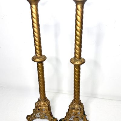 Pair of ornate gilt brass or bronze floor-standing candleholders featuring barley twist columns, leaf-motif bobèches, and decorative...