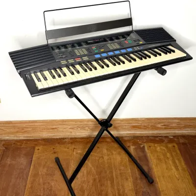 Vintage Yamaha PSR-47 electronic keyboard synthesizer with music stand attachment, displayed on a black folding X-stand.