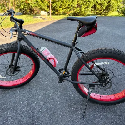 Sale Photo Thumbnail #48: Black Bronco fat-tire bicycle featuring red wheel rims, disc brakes, an under-seat bag, and a frame-mounted water bottle.