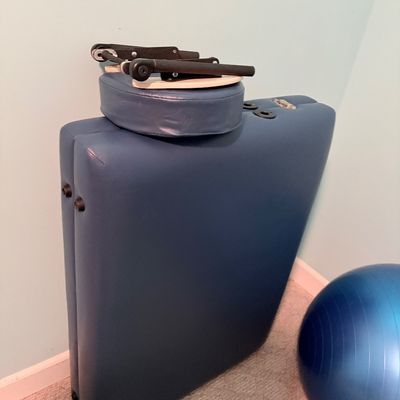 Sale Photo Thumbnail #259: Folded blue portable massage table with detachable headrest cradle and an adjacent blue exercise stability ball.