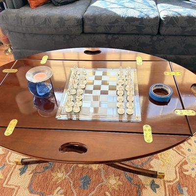 Sale Photo Thumbnail #138: Oval campaign-style butler tray coffee table with fold-down sides and brass hardware, featuring a glass chess set on top.