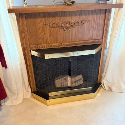 Sale Photo Thumbnail #265: Freestanding electric or gas fireplace insert housed in a traditional oak mantle surround with polished brass trim and mesh screen.