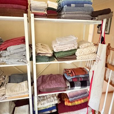 Sale Photo Thumbnail #272: Large collection of folded bath towels, bed linens, and throw blankets neatly organized on white wire shelving units.