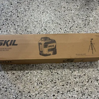 Sale Photo Thumbnail #63: Skil self-leveling 360-degree red cross line laser in original cardboard box with tripod included.