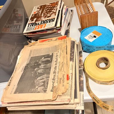 Sale Photo Thumbnail #173: Collection of vintage newspapers and sports magazines, alongside a wooden mail organizer and rolls of blue and yellow event tickets.