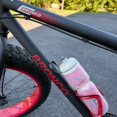 Sale Photo Thumbnail #49: Matte black Bronco fat tire bicycle frame with red wheel accents and an attached water bottle cage.