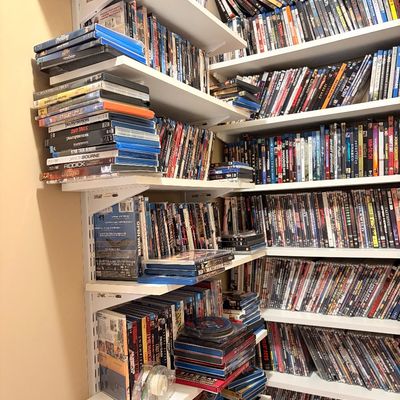 Sale Photo Thumbnail #171: Massive collection of DVDs and Blu-ray movies neatly organized on multi-tiered wall-mounted shelving units.