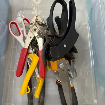 Sale Photo Thumbnail #16: Assorted household hand tools and shears inside a clear plastic storage bin, including wire cutters, pliers, and heavy-duty scissors.