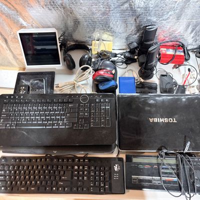 Sale Photo Thumbnail #199: Collection of assorted vintage and modern electronics, including keyboards, a Toshiba laptop, computer mice, headphones, and power adapters.