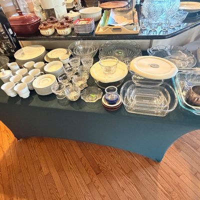 Sale Photo Thumbnail #103: Large collection of glassware, ceramic dishware, Pyrex baking dishes, and punch bowl sets arranged on a table and counter.