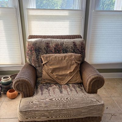 Sale Photo Thumbnail #147: Woven rattan armchair with dark wood feet, upholstered in a nature-patterned tapestry fabric, complete with a accent pillow.