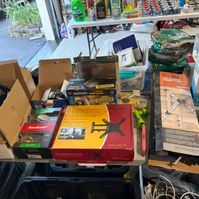 Sale Photo Thumbnail #78: Assorted household hardware, tools, and electronics organized on a table, including a VideoSecu articulating wall mount, Pony framing clamp, and Thermacell Patio Shield.