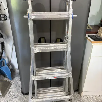 Sale Photo Thumbnail #54: Foldable aluminum multi-position step ladder with top wheels, showing light wear from use.