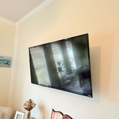 Sale Photo Thumbnail #292: Modern Vizio flat-screen television mounted on a wall above a table with tabletop accessories.