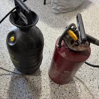 Sale Photo Thumbnail #56: Two pump-style lawn and garden compression sprayers, one black and one burgundy, showing light wear from use.