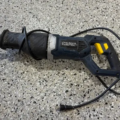 Sale Photo Thumbnail #64: Chicago Electric corded reciprocating saw with a dark blue and black housing and yellow trigger switch.