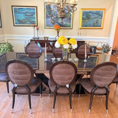 Sale Photo Thumbnail #113: Contemporary high-gloss dining table set with eight oval-back upholstered chairs, paired with framed artwork in the background.