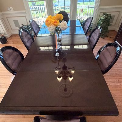 Sale Photo Thumbnail #112: Contemporary high-gloss dark wood dining set including a long polished table and eight matching rounded-back chairs with cushioned upholstery.