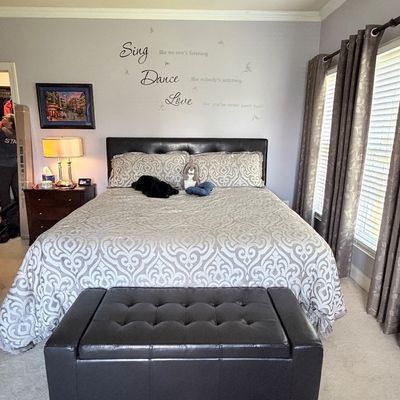 Sale Photo Thumbnail #312: Contemporary bedroom set including a dark brown tufted faux leather bed frame with matching storage ottoman, a nightstand, and patterned bedding.