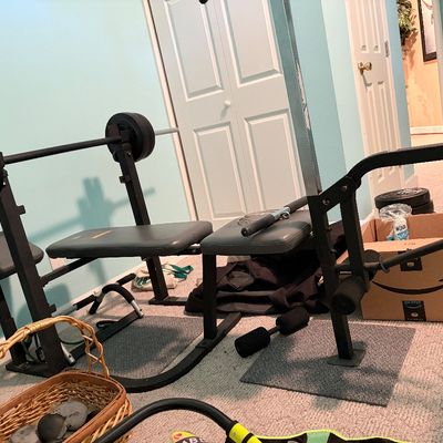 Sale Photo Thumbnail #177: Black metal weight bench setup with a loaded barbell, padded seats, and additional exercise equipment.