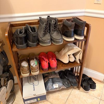 Sale Photo Thumbnail #159: Wooden three-tier shoe rack filled with an assortment of men's and women's footwear, including boots, boat shoes, sneakers, and sandals.