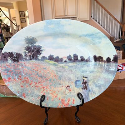 Sale Photo Thumbnail #89: Large oval decorative ceramic serving platter featuring Claude Monet's impressionist painting "Poppies", displayed on a black wrought iron stand.