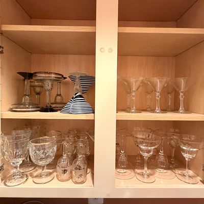 Sale Photo Thumbnail #105: Collection of assorted glassware inside a cabinet, featuring etched wine glasses, martini glasses, coupe glasses, and striped specialty stemware.