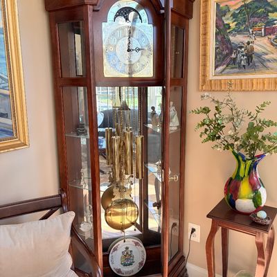 Sale Photo Thumbnail #128: Traditional wood grandmother or grandfather clock cabinet with side glass display shelves, brass weights, pendulum, and ornate face dial.
