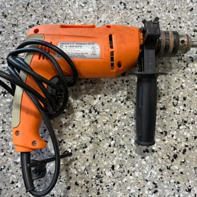Sale Photo Thumbnail #62: Corded orange and black 1/2-inch hammer drill with auxiliary side handle and chuck key attached.