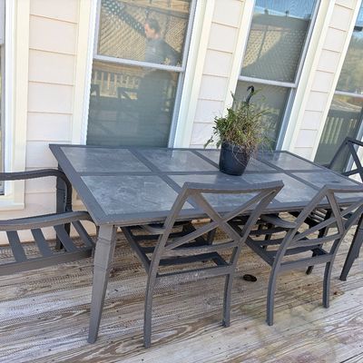Sale Photo Thumbnail #97: Outdoor patio dining set featuring a slate-tile top rectangular table and six dark metal cross-back chairs.