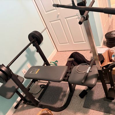 Sale Photo Thumbnail #256: Weider multi-station home gym system featuring a weight bench, barbell set, lat pulldown, and leg extension attachments.