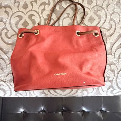 Sale Photo Thumbnail #303: Coral pink Calvin Klein leather tote bag featuring drawstring detailing and brown shoulder straps.
