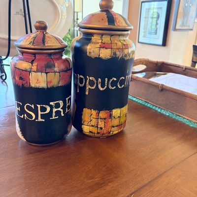 Sale Photo Thumbnail #144: Pair of hand-painted ceramic canisters labeled "Espresso" and "Cappuccino" with lids, featuring colorful abstract patch motifs on a black background.