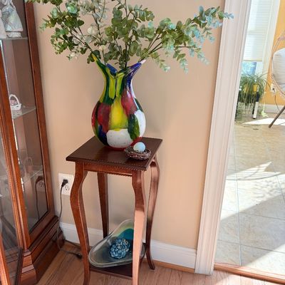 Sale Photo Thumbnail #134: Traditional dark wood plant stand with cabriole legs, supporting a colorful Murano-style art glass vase with faux eucalyptus greenery.
