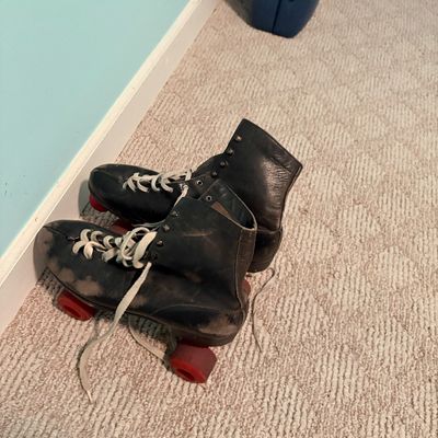 Sale Photo Thumbnail #260: Pair of vintage black leather roller skates with red wheels and white laces, showing significant wear and scuffing from use.