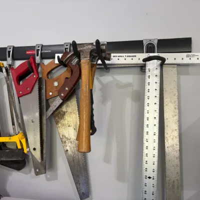 Sale Photo Thumbnail #11: Rubbermaid FastTrack wall-mounted organizer rack holding an assortment of hand tools, including saws, hammers, and a drywall T-square.