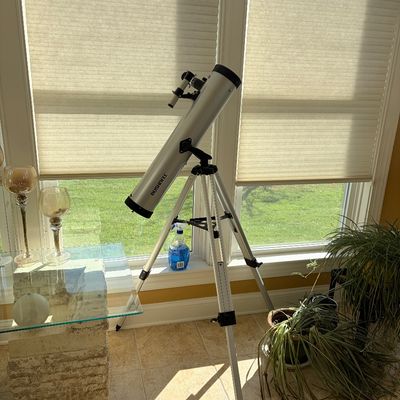 Sale Photo Thumbnail #118: Bushnell silver reflector telescope mounted on an adjustable aluminum tripod, positioned indoors near a sunlit window.