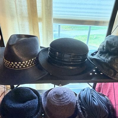 Sale Photo Thumbnail #270: Collection of women's vintage hats displayed on a metal shelf, including a studded wide-brim straw hat, a black felt structured hat, a bucket hat, and knit caps.