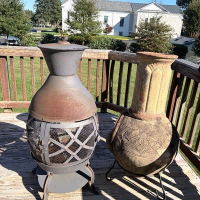 Sale Photo Thumbnail #98: Metal outdoor chiminea with mesh screen next to a decorative terra cotta chiminea pot on a wrought iron stand.