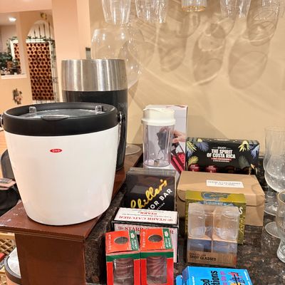 Sale Photo Thumbnail #184: Collection of barware and entertaining accessories, including an OXO ice bucket, wine glasses, shot glasses, a mini blender, and boxed novelty items.